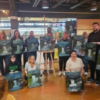 Students displaying their waterfall oil paintings with instructor Kevin Wolff